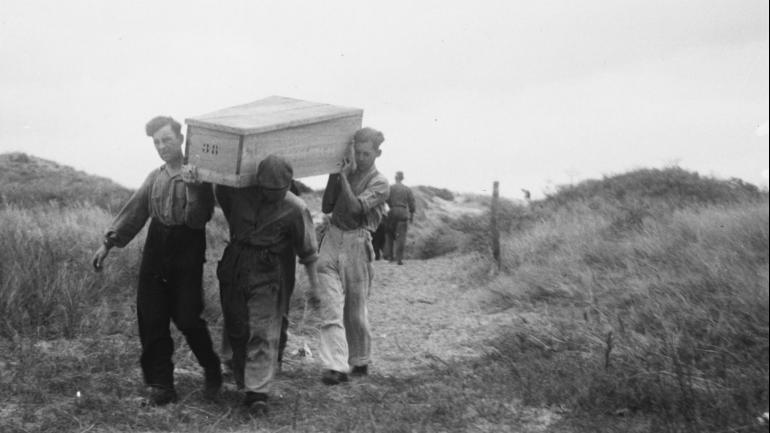 Stoffelijk overschot wordt weggedragen van de Waalsdorpervlakte. Bron: fotograaf P. van der Ham/Anefo, collectie Nationaal Archief 